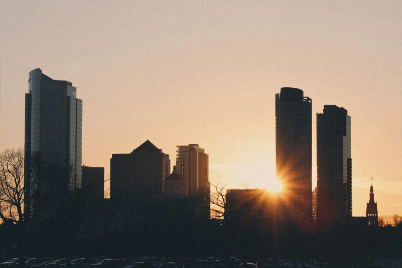 a city skyline with a setting sun in the background