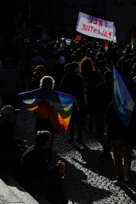 several people are walking with their backs turned and holding rainbow flags and signs