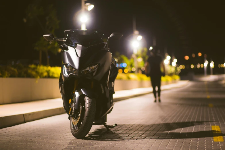 a man walking down a sidewalk near a parked motorcycle