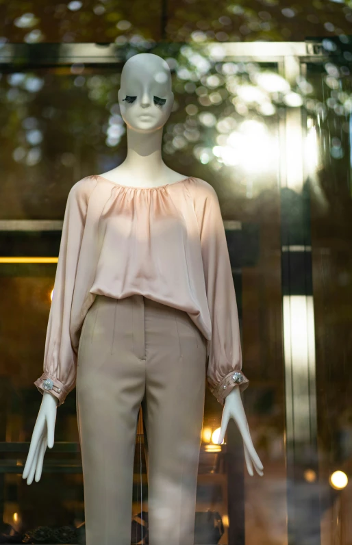 a mannequin wearing beige clothes stands in front of a window display