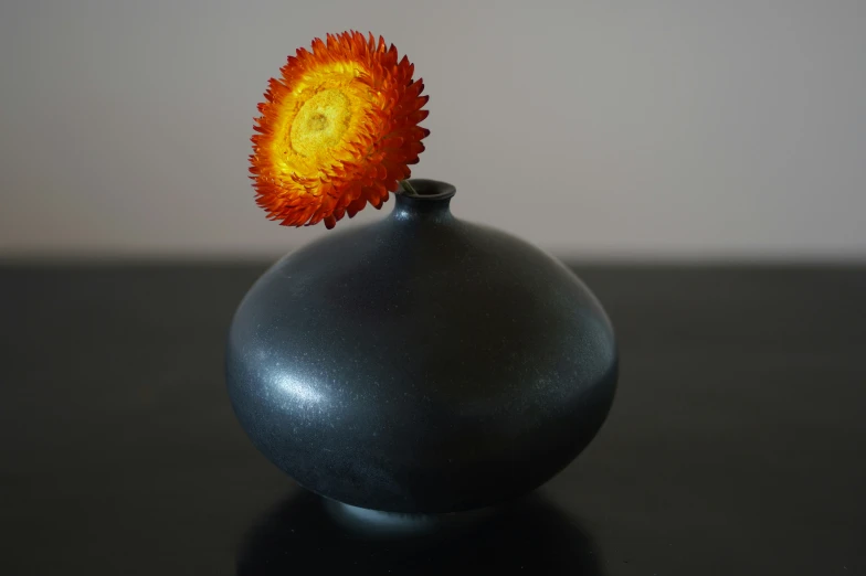 a grey vase with a flower sticking out of it