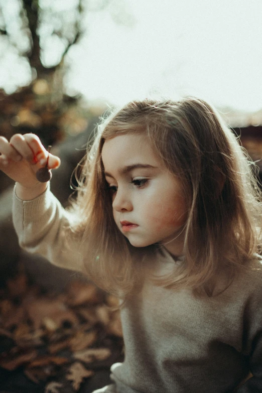 a  is holding soing while sitting on leaves