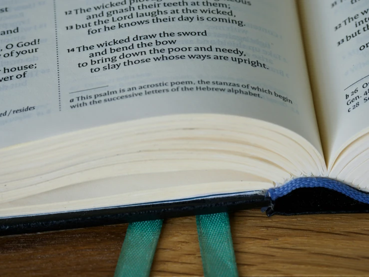 an open book on top of a wooden table with blue ribbon