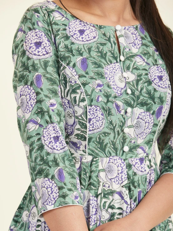 a woman is wearing a dress with a flower pattern