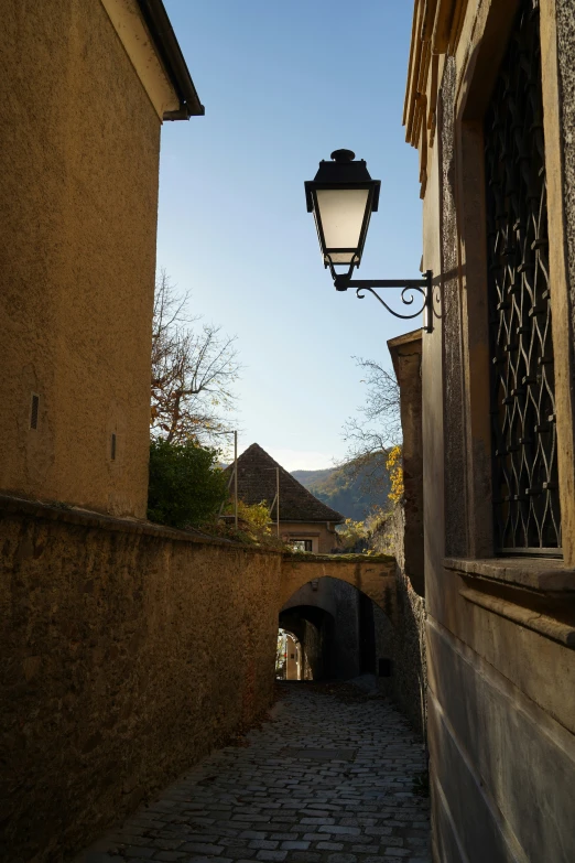 an old street light over a narrow bricked road