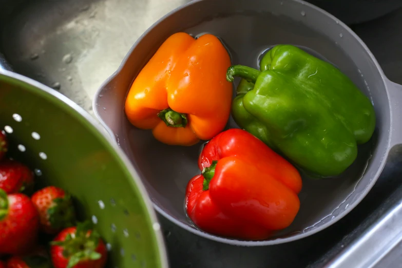 three peppers in a bowl of strawberries