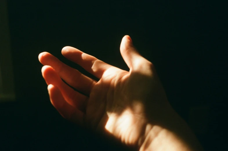a person in dark room holds their hand up