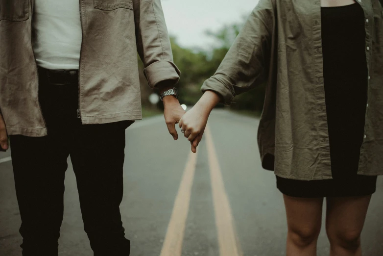 the two young people hold hands as they walk down the street