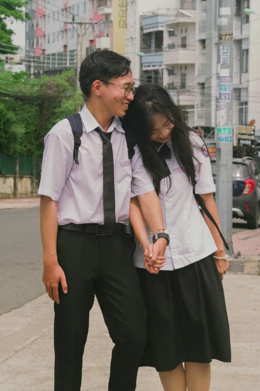 two people holding hands walking together on a sidewalk