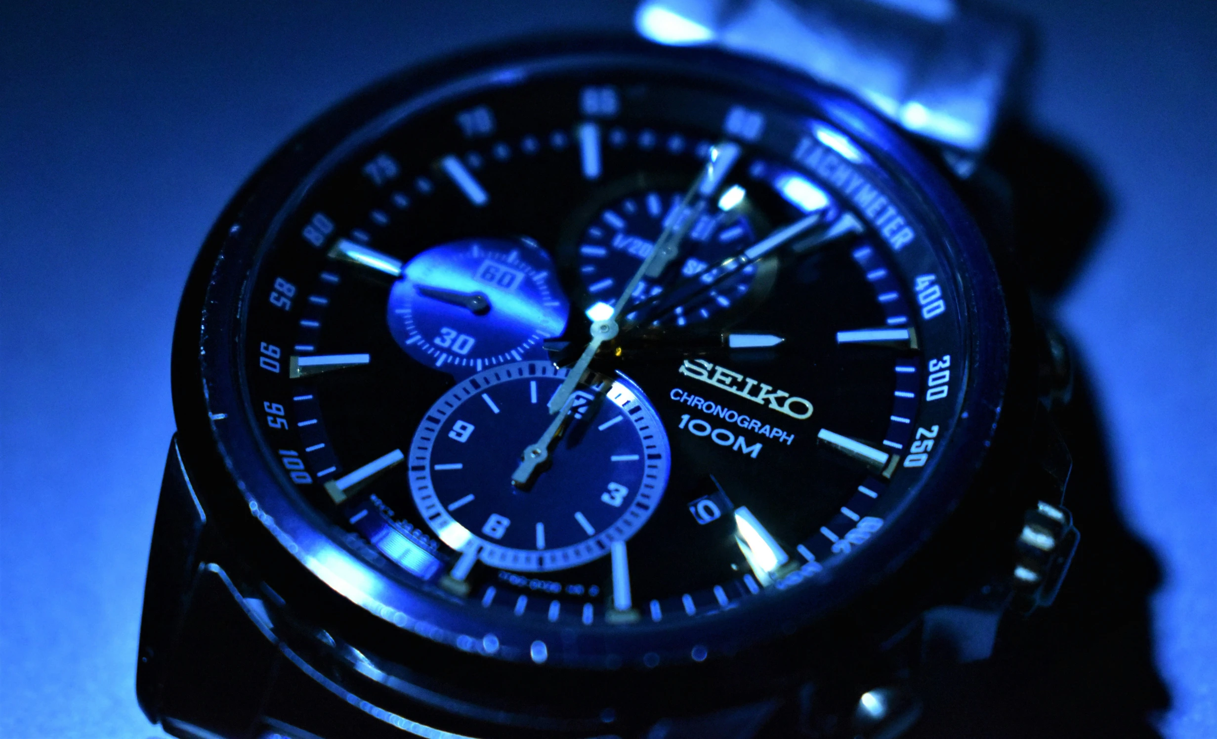 a watch with dark blue dial and hands is lit by a spotless light