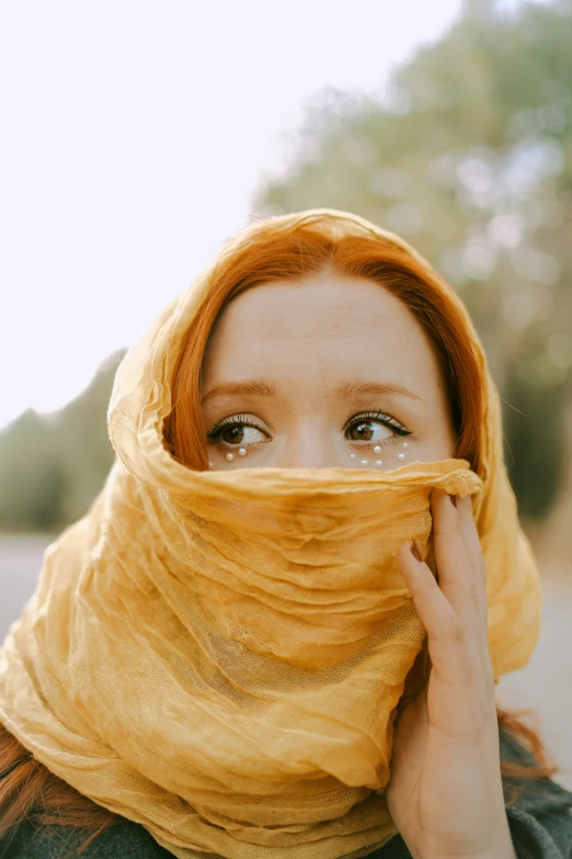 a woman with a yellow scarf covering her face