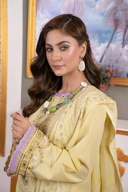 a woman in a yellow outfit standing by some paintings