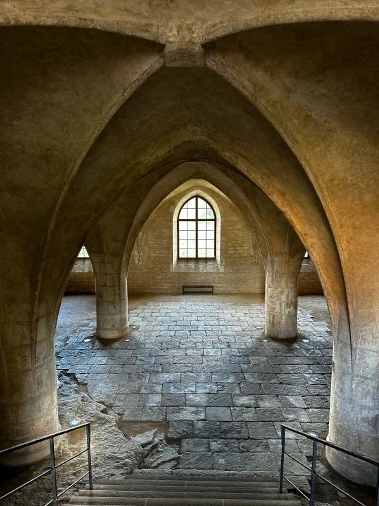 an archway leads to a stone wall that looks like it has a window in it