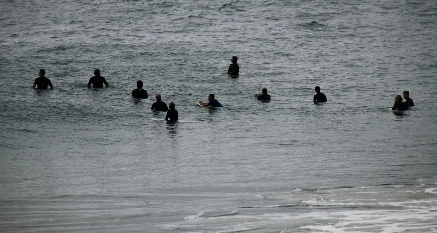 people standing in shallow water with surfboards on a rainy day
