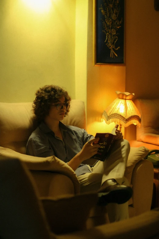 a woman is sitting on a couch in the light of a lamp