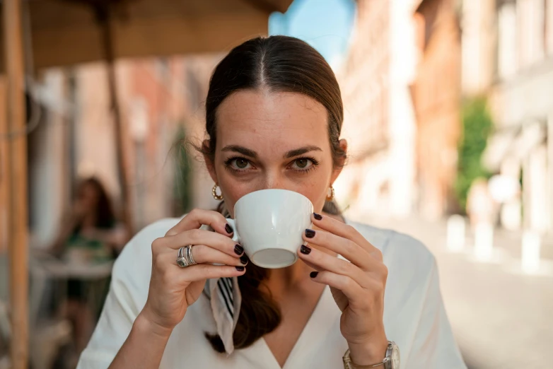 a young woman drinks coffee out of a white mug