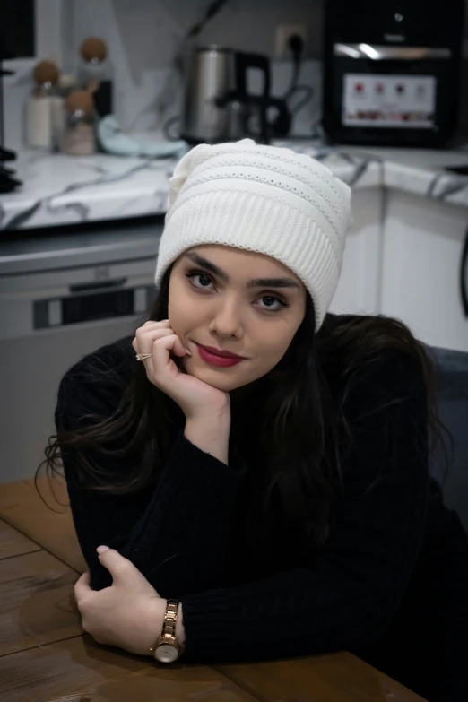 a woman wearing a white hat sitting in a kitchen