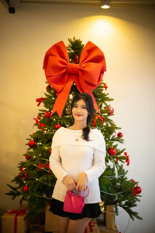 a beautiful young woman posing for a po in front of christmas tree