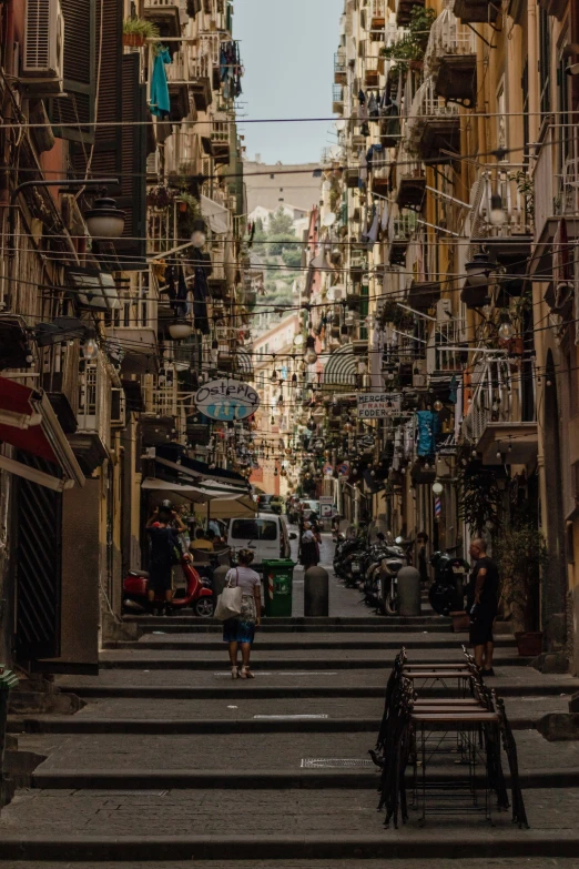 people walking down a steep city street in the middle of buildings