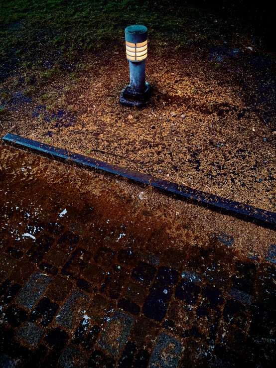 a sidewalk lamp on a brick path at night