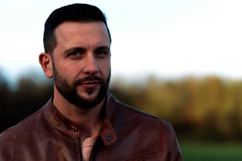 a man in a brown leather jacket looking off into the distance