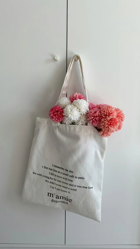 a bag hanging on the wall with some pink flowers on it