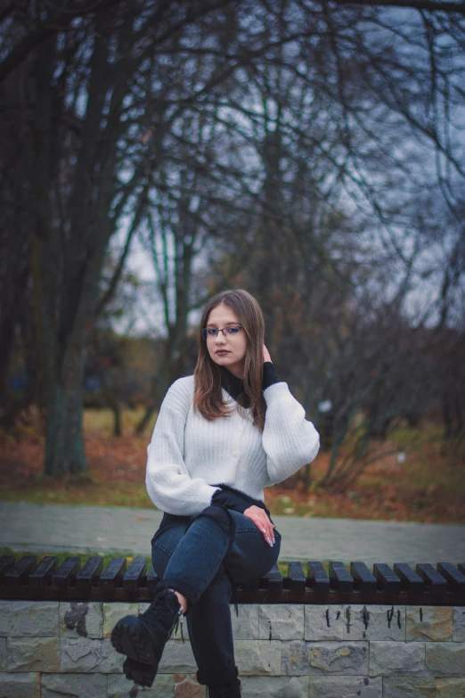 young lady with her eyes shut sits on a bench