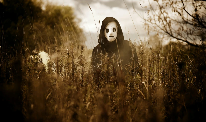 a creepy person with a fake mask hiding in tall grass