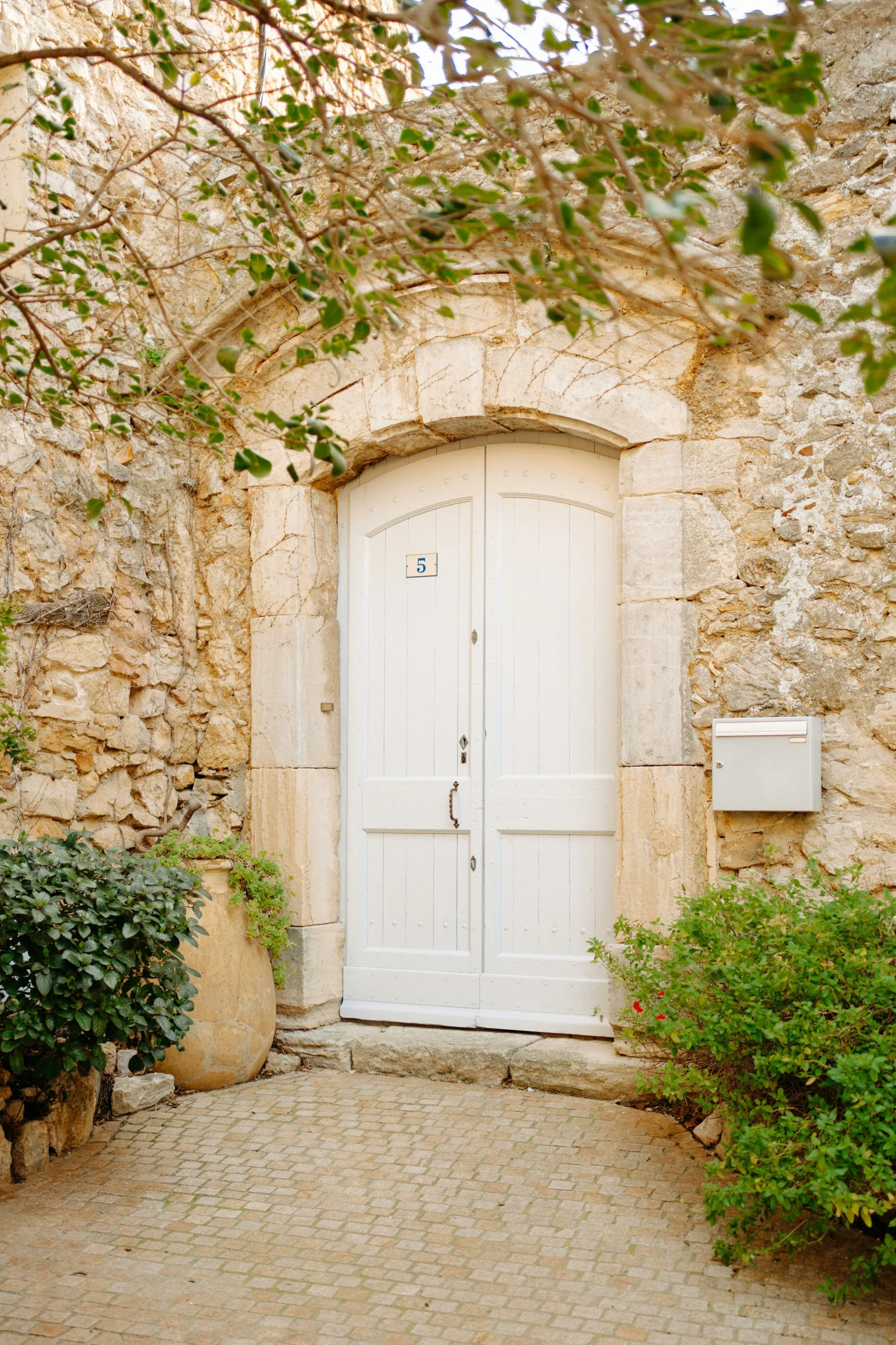 a couple of white doors and bushes near a building