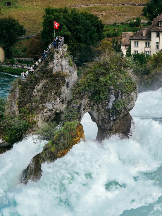 tourists enjoying a large waterfall near buildings