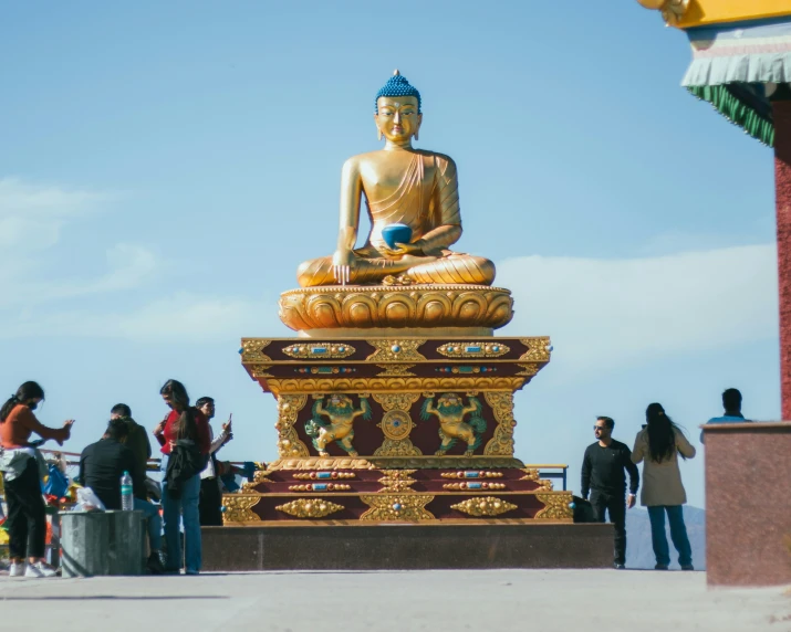 a golden buddha statue sitting on top of a golden pedestal