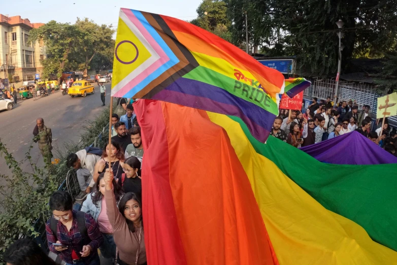 a group of people on a street holding a rainbow flag