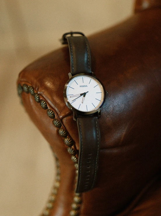 the watch is on the brown leather cushion