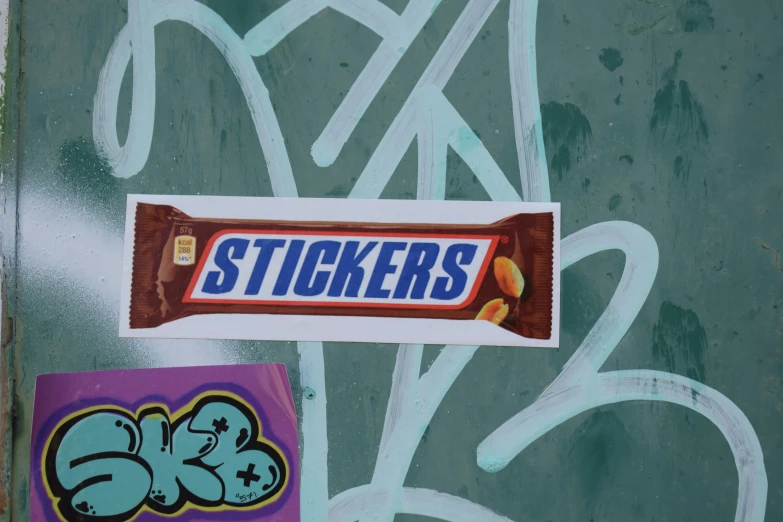 two stickers attached to a wall with graffiti