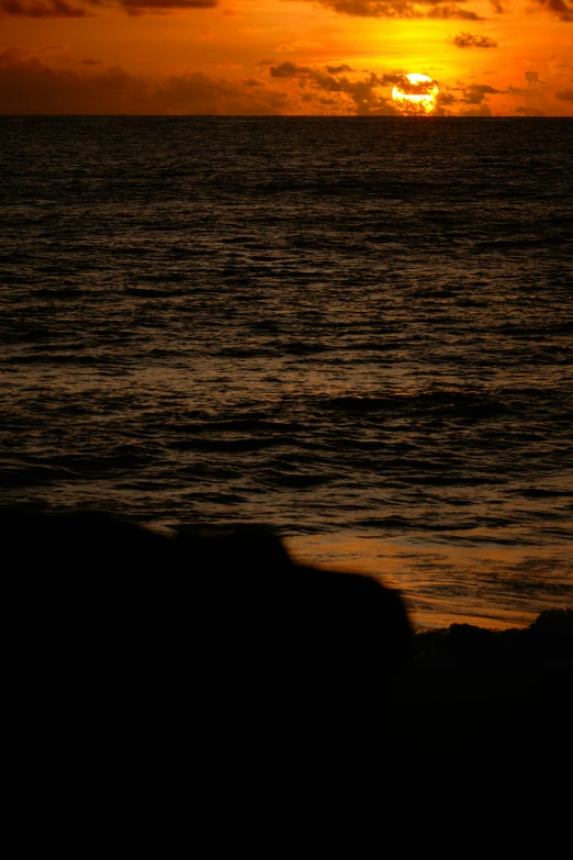 the sun sets behind the horizon over the ocean