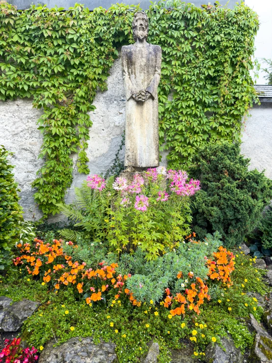 a stone statue covered with vines next to a garden