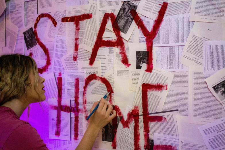 a woman is writing on the wall with some red spray paint