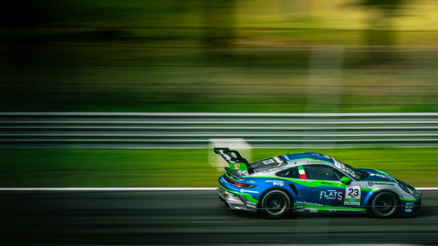 a car with a green and blue paint scheme driving on a race track