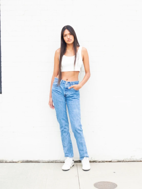 the woman is posing next to a white wall