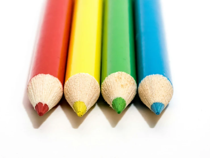 four colored pencils that are on a table