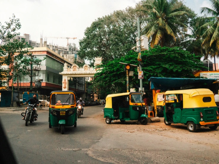 green and yellow tuks sitting on the side of a road