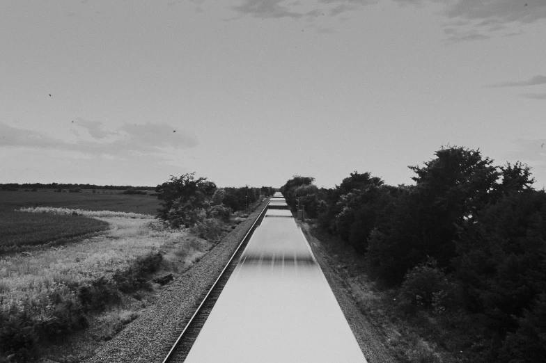 an overhead view of a train track lined with bushes and trees