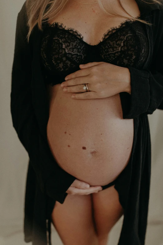 a pregnant woman wears a black  and shows her slender belly