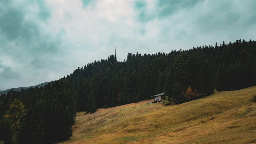 a mountain with a lone cabin sitting on top