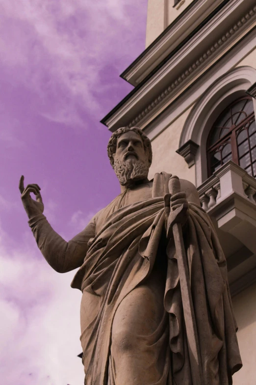 the statue of a man wearing a cape near a building