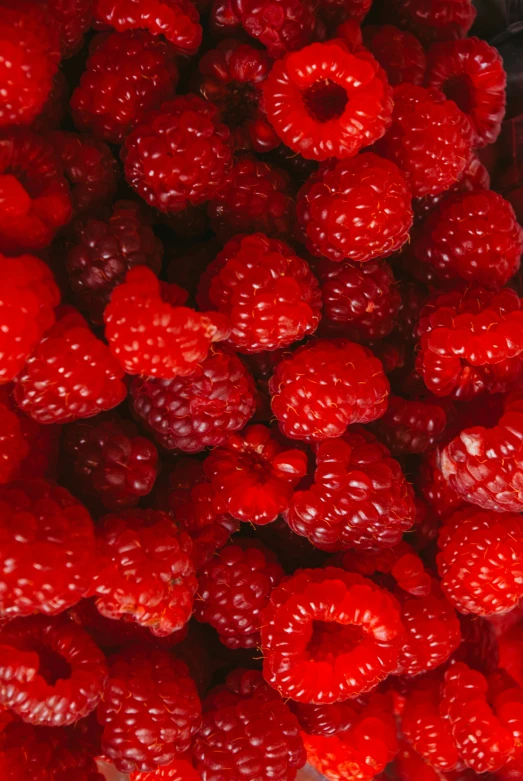 fresh raspberries piled on each other for sale at a store