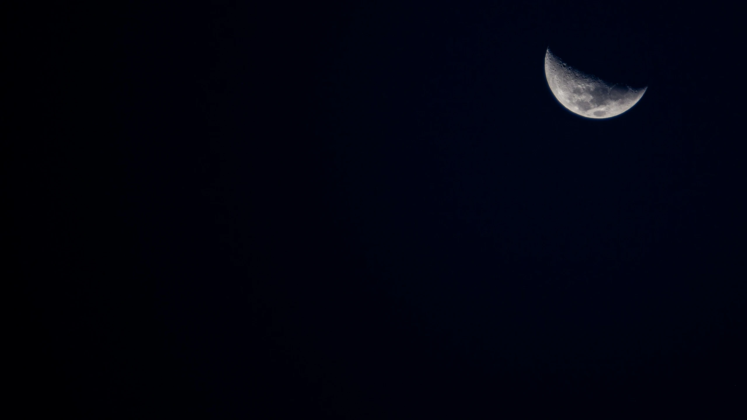 a half moon seen through the dark sky with the moon in the background