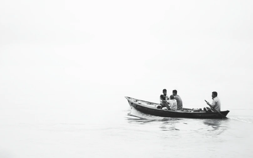 four people riding in a small boat with their dog on a foggy day