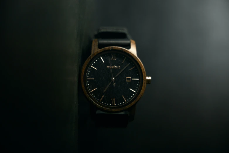 a wooden watch hanging on the wall near black walls