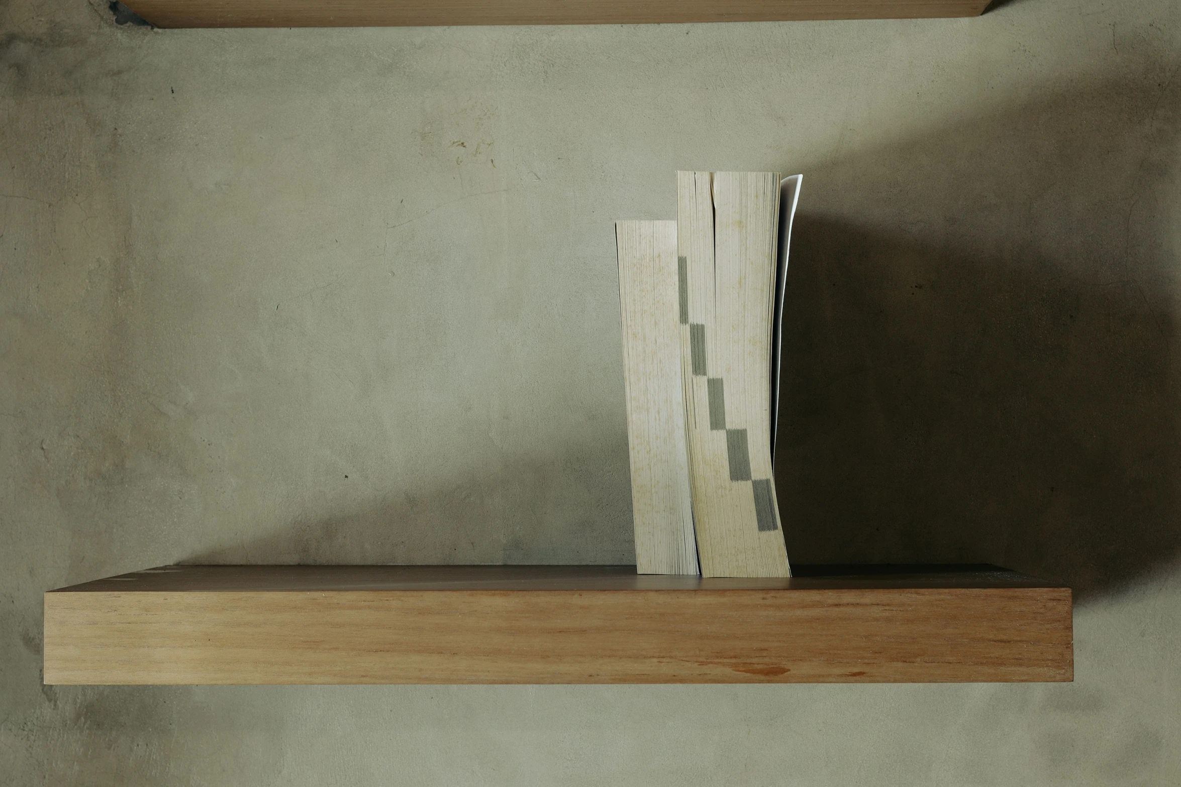 two folded pieces of paper sit on a shelf